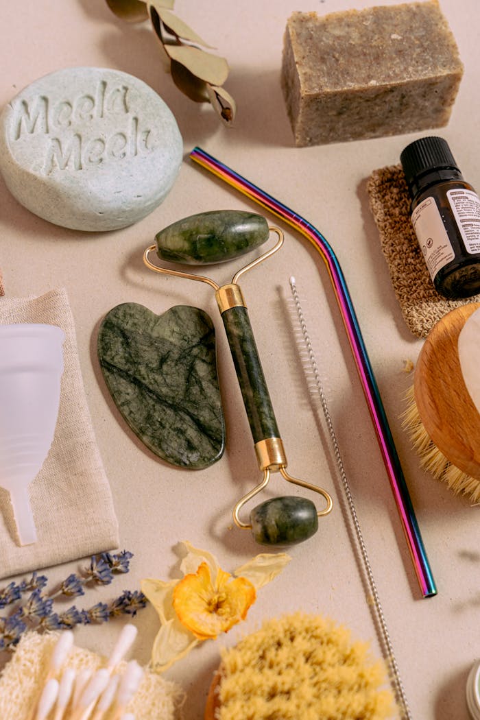 Flat lay of eco-friendly self-care products including jade roller, menstrual cup, and sustainable items.
