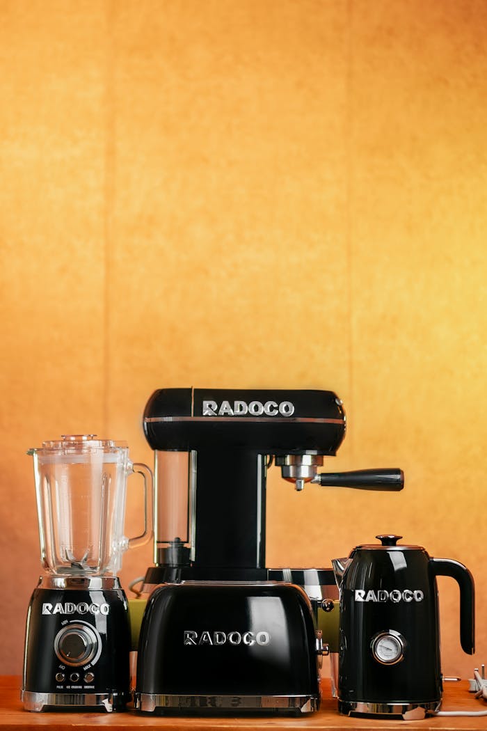 Modern black kitchen appliances including blender, mixer, and kettle with warm background.