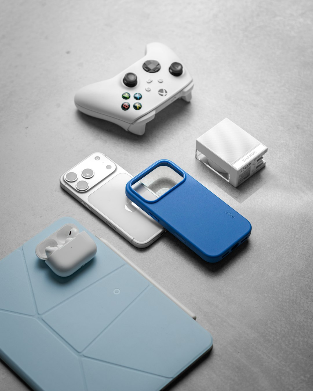 white-gaming-controller-smartphone-and-earbuds-on-surface-kdtilyijd50